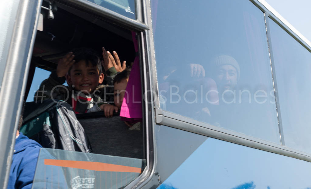 Niños afganos saludan desde el autobús que les devolverá a Atenas. Foto: Pablo Ibáñez.