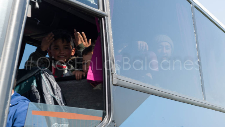 Niños afganos saludan desde el autobús que les devolverá a Atenas. Foto: Pablo Ibáñez.